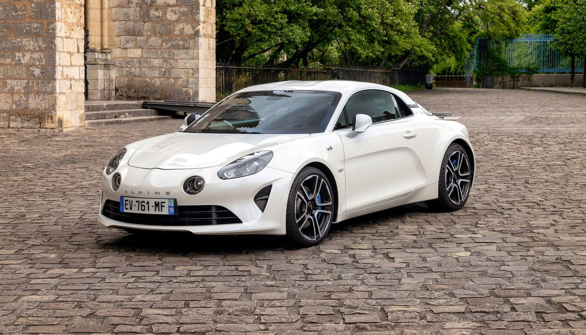 White Alpine A110 seen from the front three-quarter view on a cobbled square