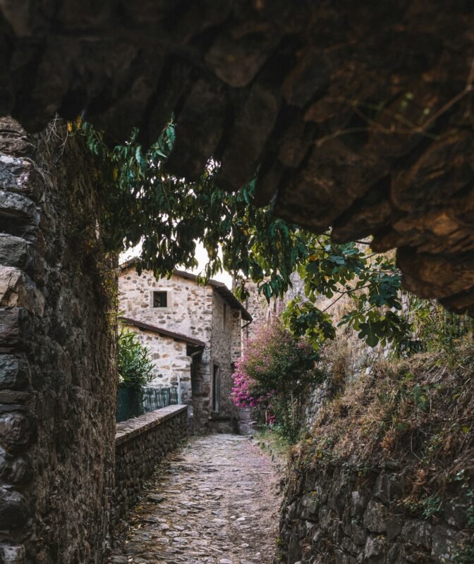a cobblestone street with a stone building in the background