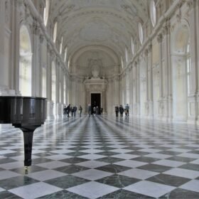 a grand piano in a large hall with a checkered floor